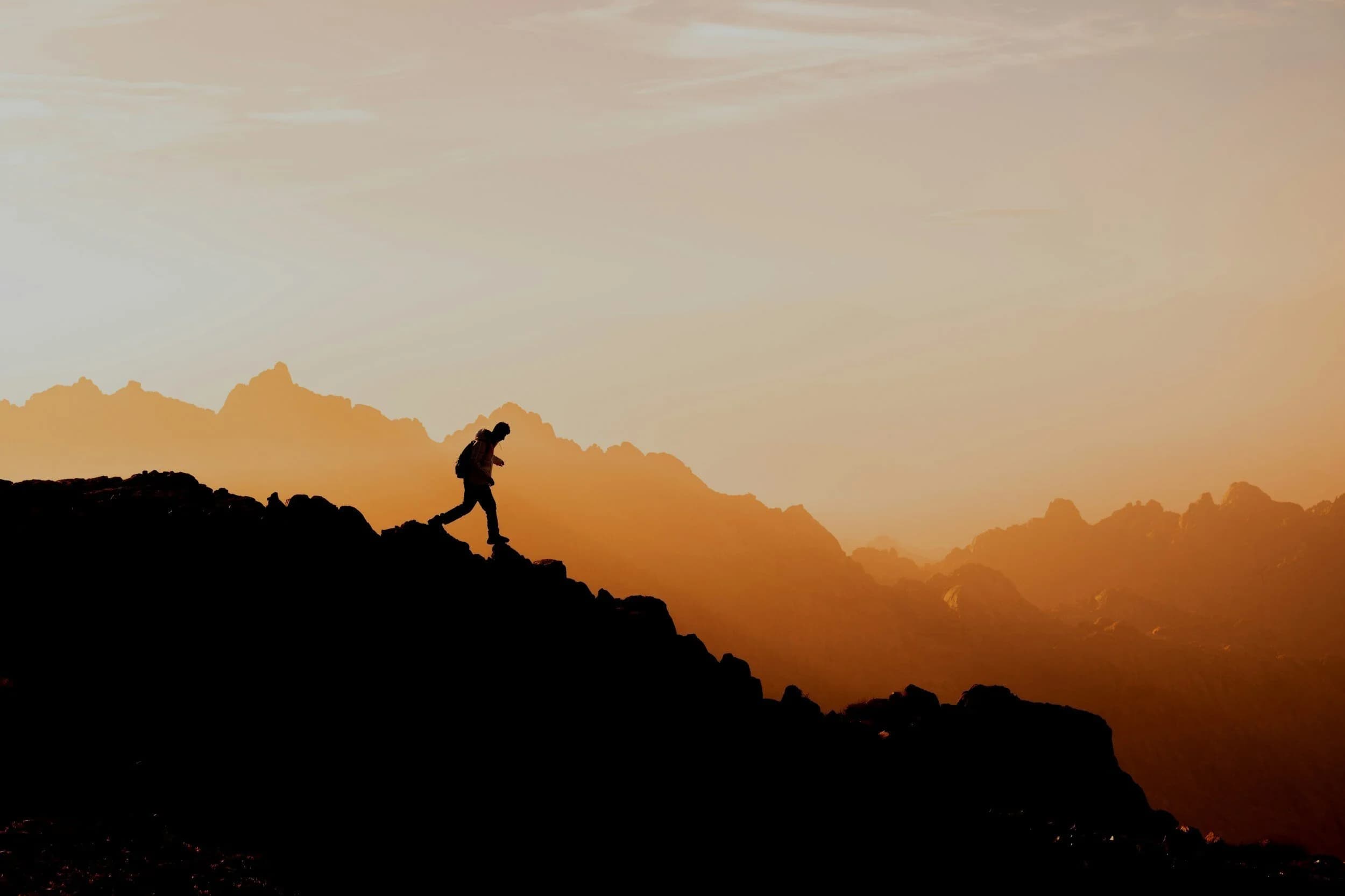 Person walking toward mountains at sunrise, representing longevity and health optimization